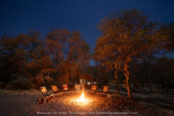 Safari chairs around a campfire at night by Stu Porter, Wild4 Photography Tours